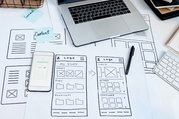 Website development planning with laptop smartphone and design sketches